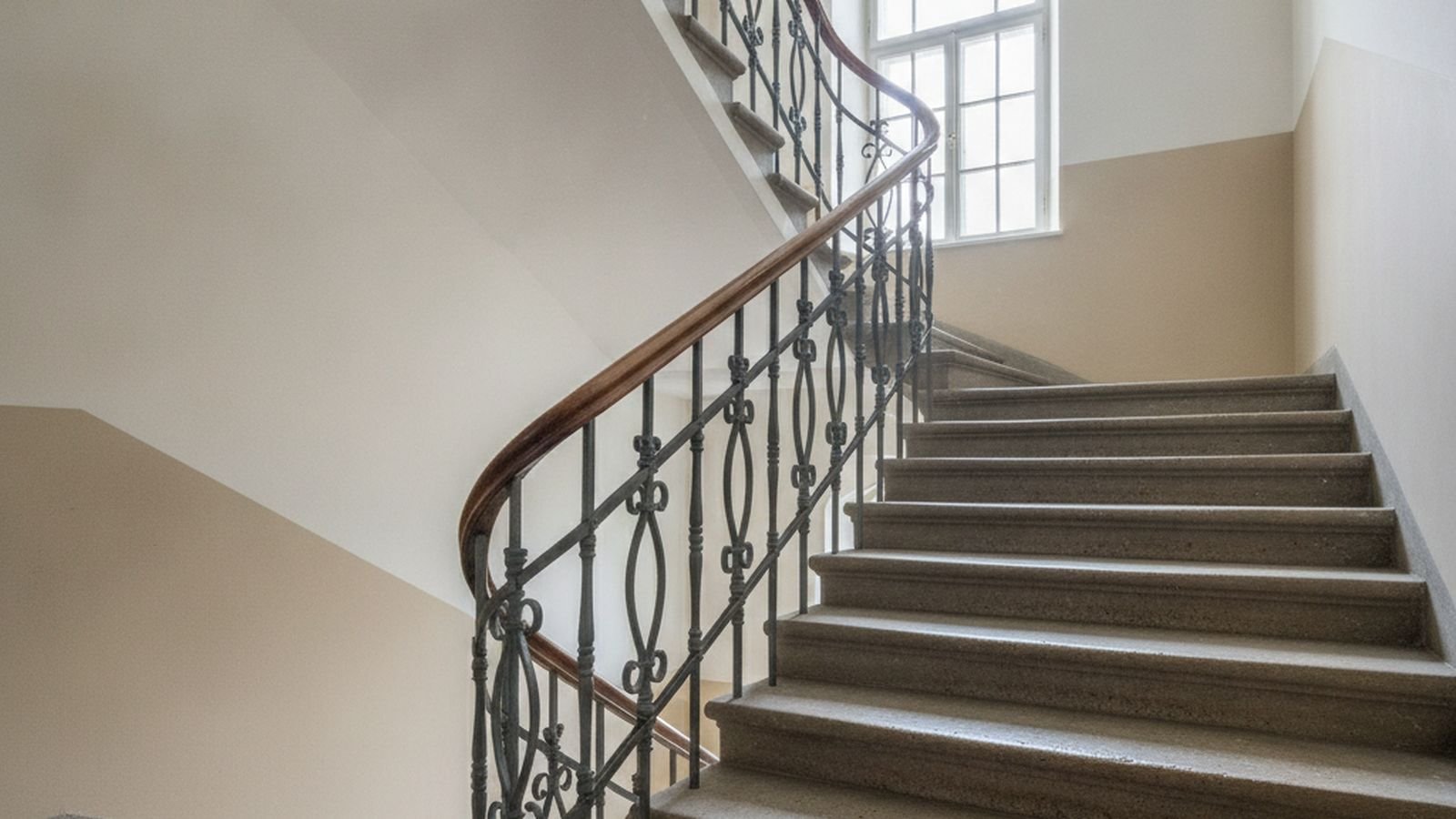 Frisch gestrichenes Altbautreppenhaus mit geschwungenem Handlauf und Tageslicht